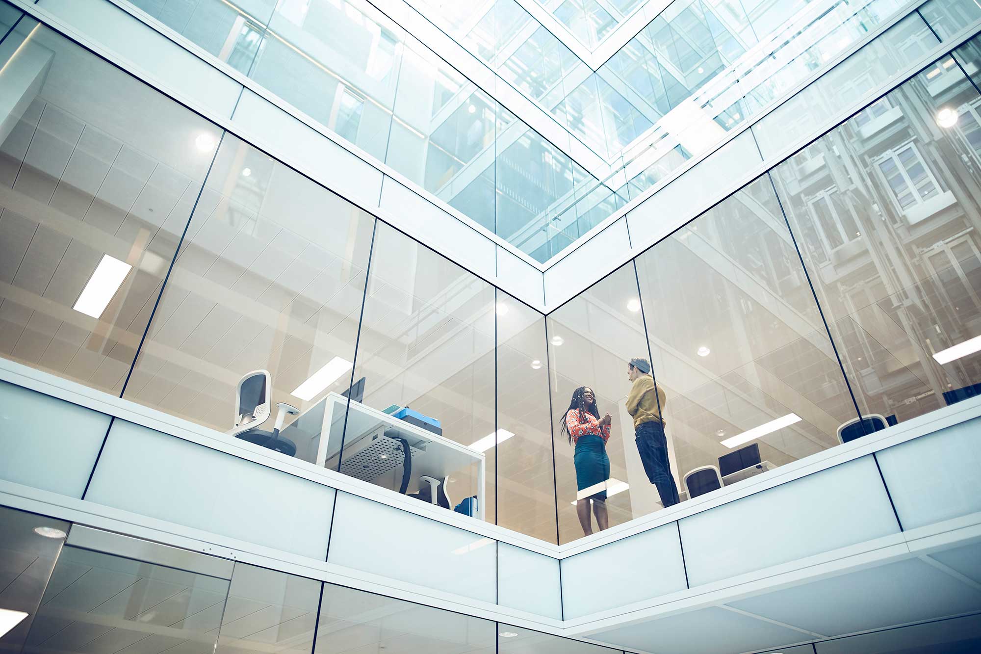 Två kollegor i en modern kontorsbyggnad med glasfasad